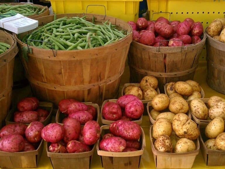 bushel baskets of potatoes and green beans at a farmers market