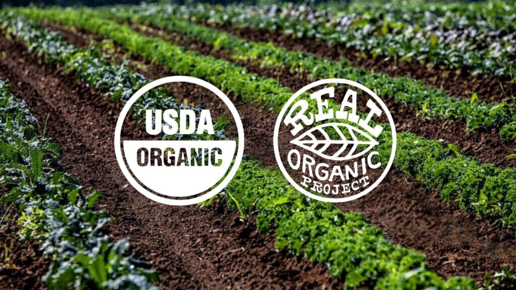 The USDA Organic Seal and the Real Organic Project Seal against a row of crops.