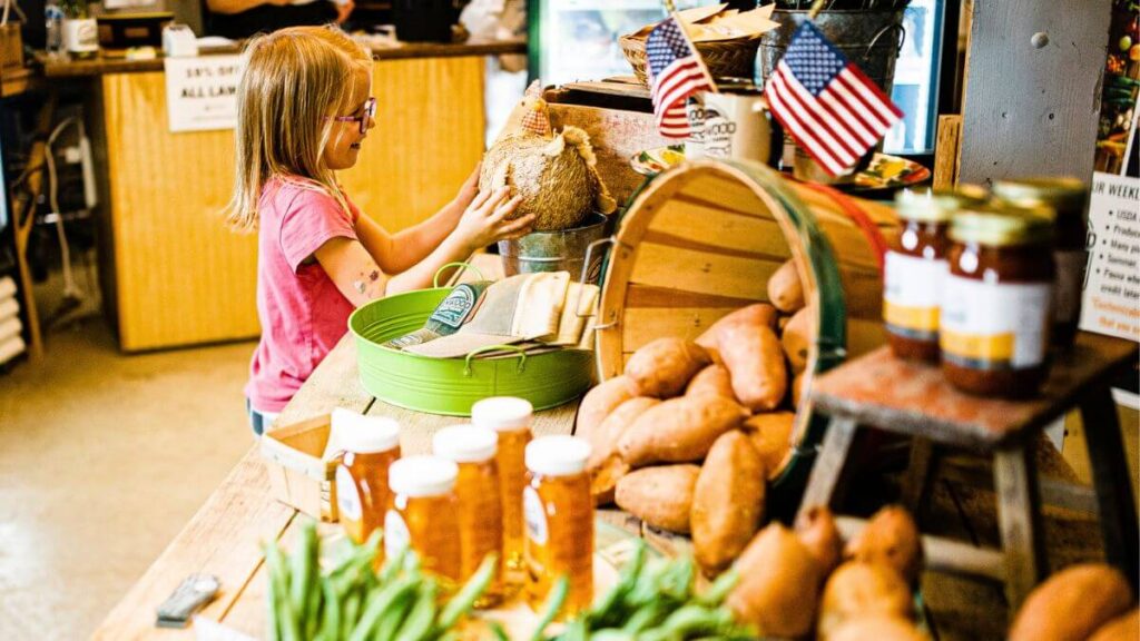 a child looks over a table full of fresh produce inside the Elmwood farm store.